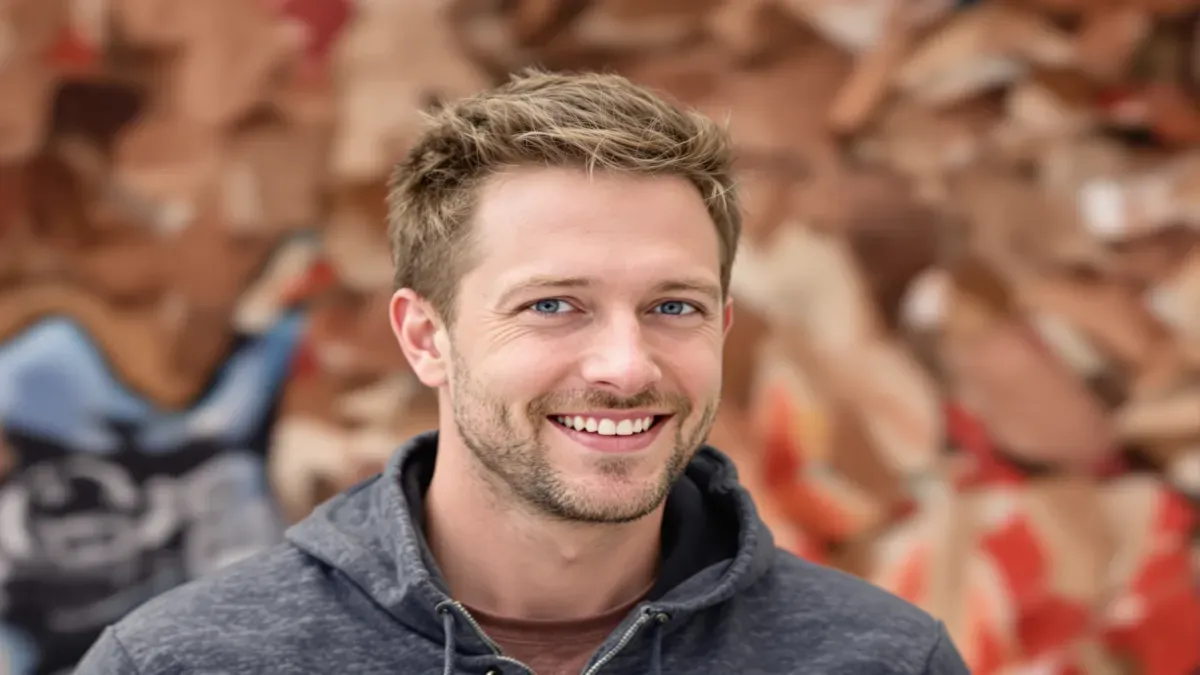 Homme souriant en hoodie gris sur fond flou